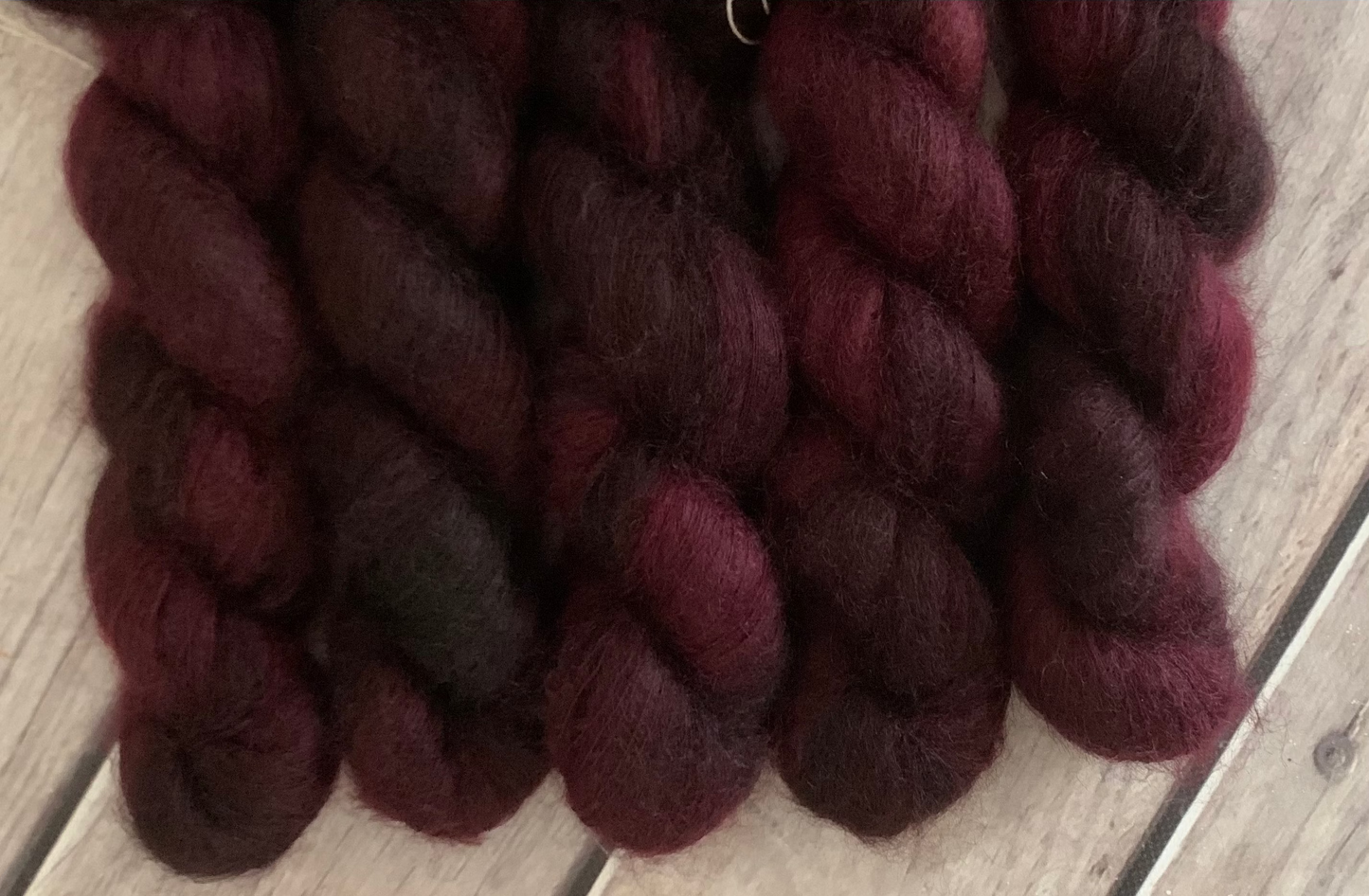 Burgundy yarn skeins on a wooden surface