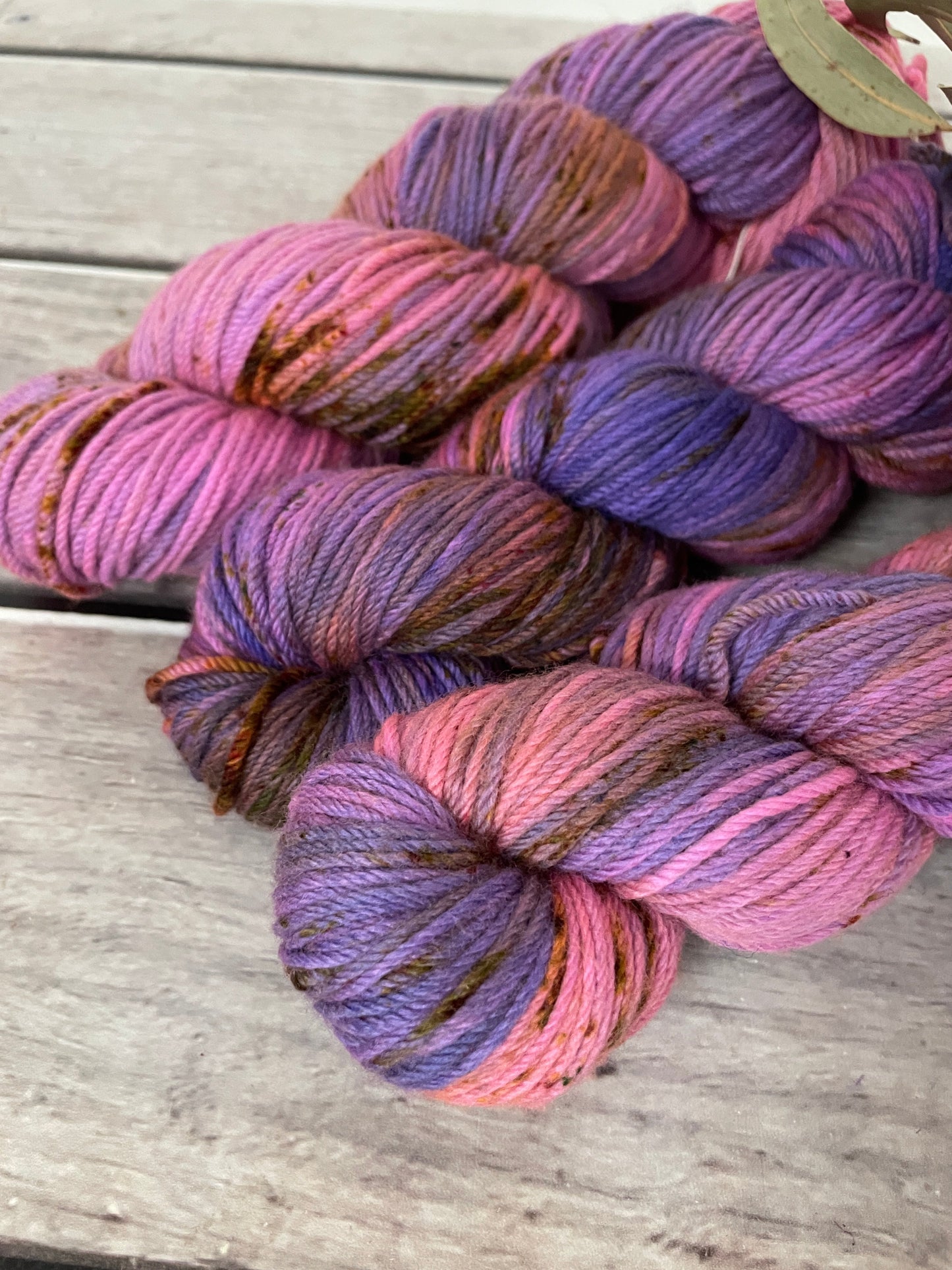 Three skeins of multicolored yarn on a wooden surface