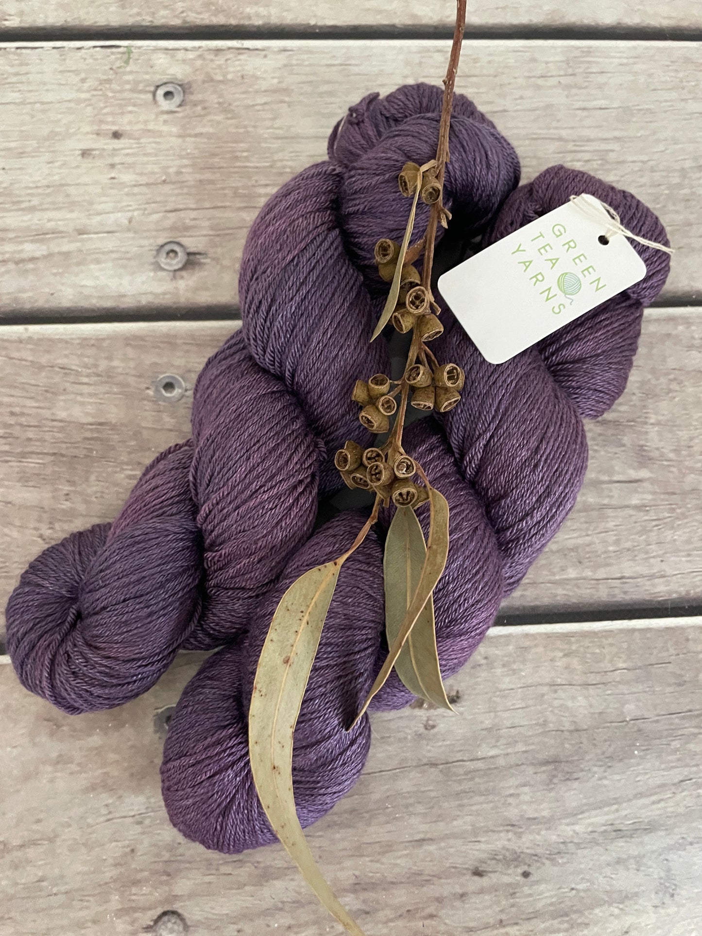 Purple skein of yarn with a tag on a wooden surface