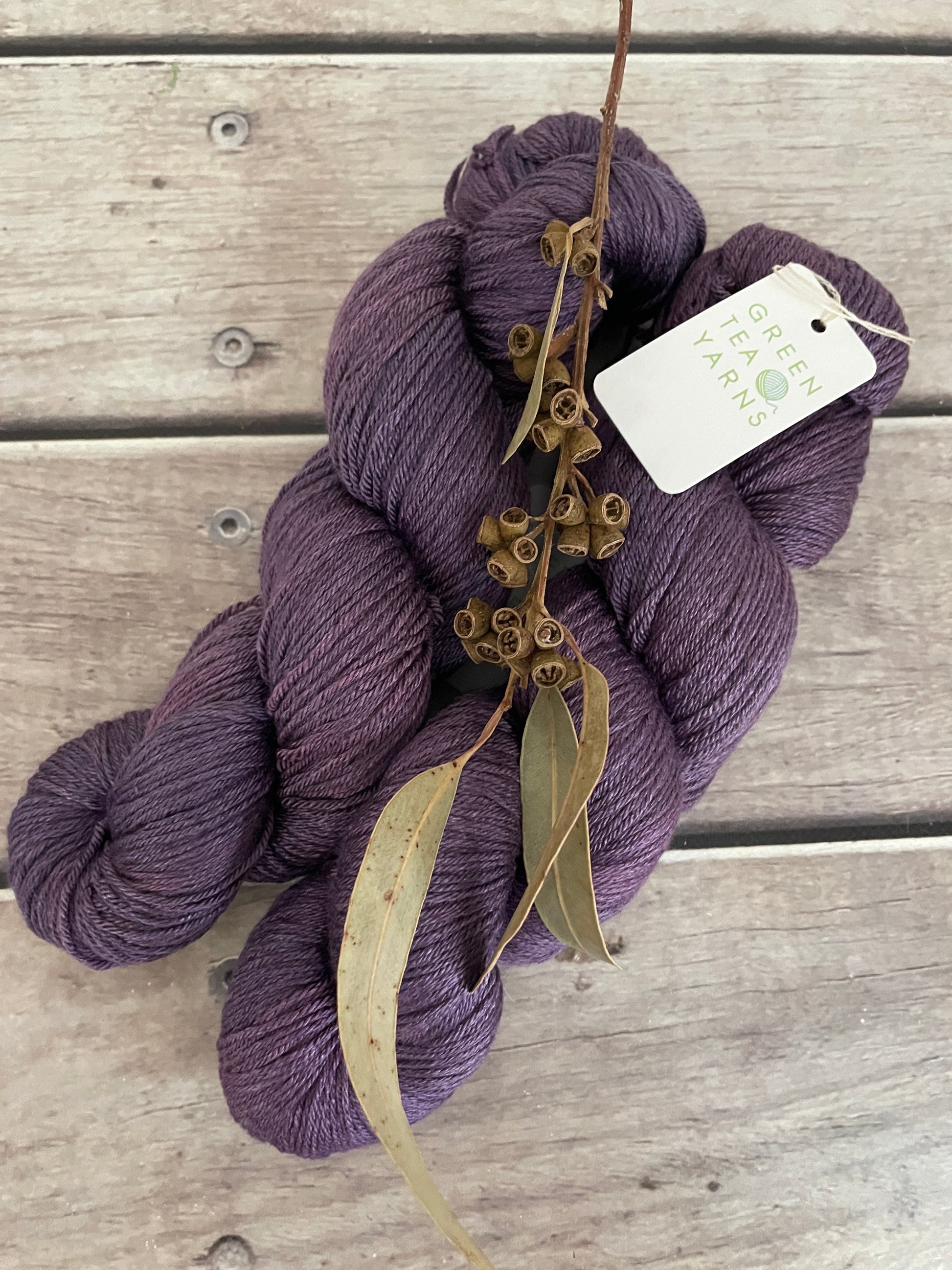 Purple skein of yarn with a tag on a wooden surface