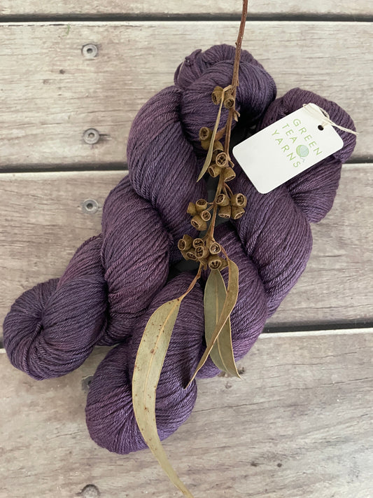 Purple skein of yarn with a tag on a wooden surface
