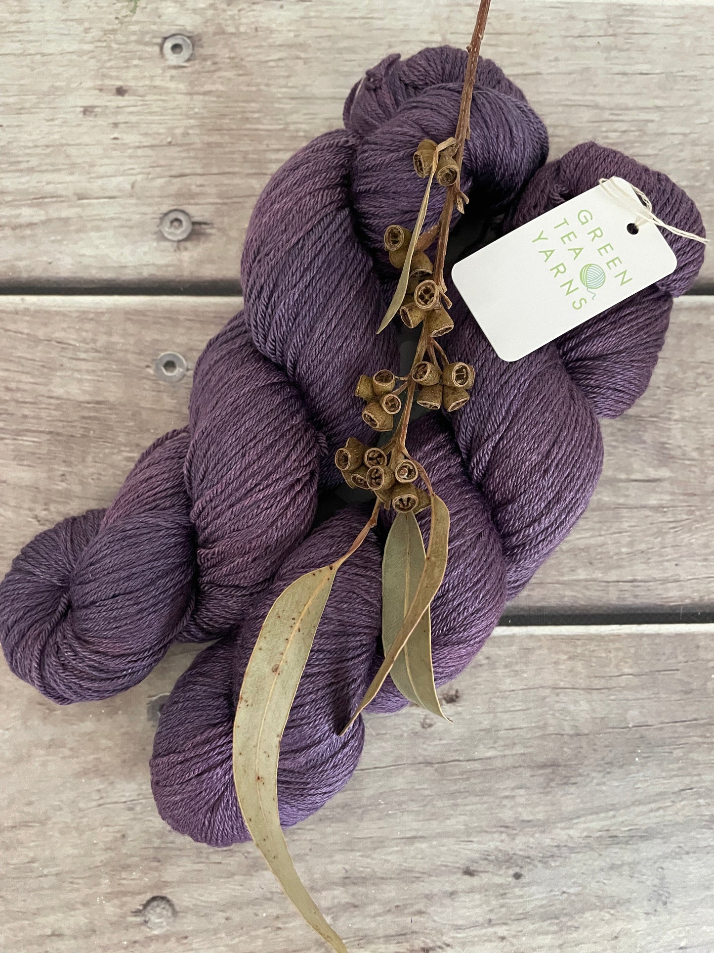 Purple yarn skein with a tag on a wooden surface