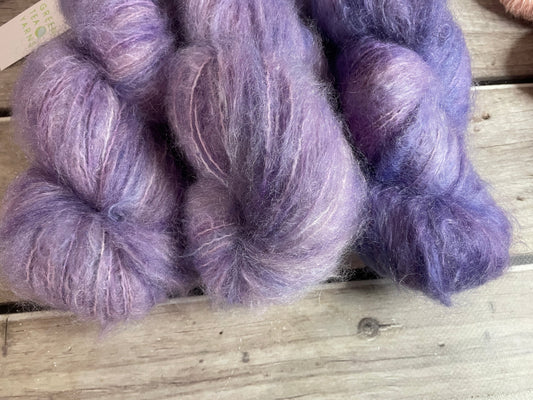 a fluffy mohair 8 ply yarn sits on a wooden board. 